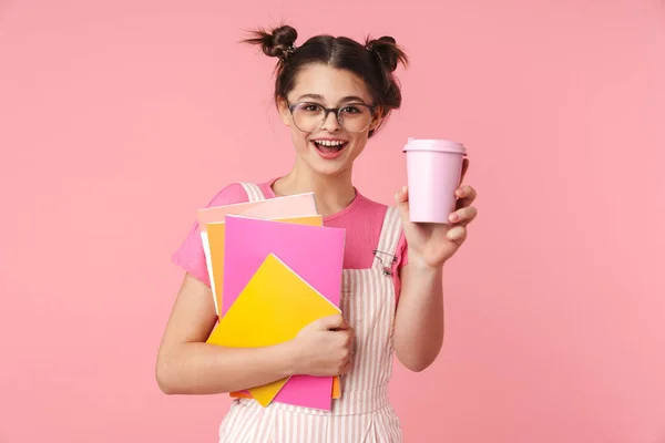 写真の幸せな魅力的な女の子で眼鏡保持運動本と紙コップ隔離されたピンクの背景 — ストック写真