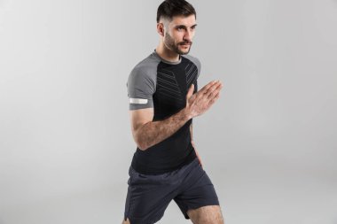 Gri arka planda tek başına çalışırken spor giyim sektöründe egzersiz yapan genç ve güçlü bir adamın görüntüsü