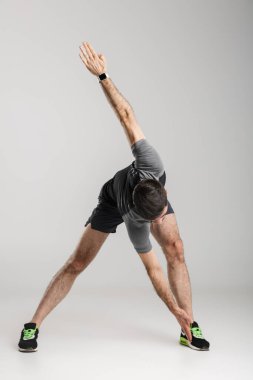 Gri arka plan üzerinde izole bir şekilde çalışırken spor giyim sektöründe spor yapan beyaz bir adamın görüntüsü.