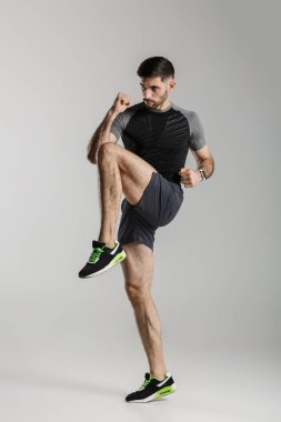 Gri arka plan üzerinde izole bir şekilde çalışırken spor giyim sektöründe spor yapan beyaz bir adamın görüntüsü.