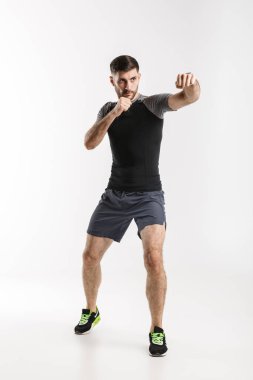 Beyaz arka planda tek başına çalışırken spor giyim sektöründe beyaz bir sporcunun vuruşunun görüntüsü