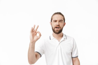 Sıradan kıyafetler giyen çekici genç sakallı adam beyaz arka planda izole bir şekilde duruyor.