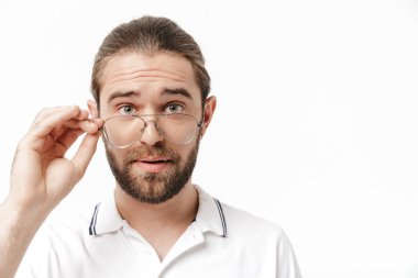 Sıradan kıyafetler giyen çekici genç sakallı adam beyaz arka planda tek başına duruyor.