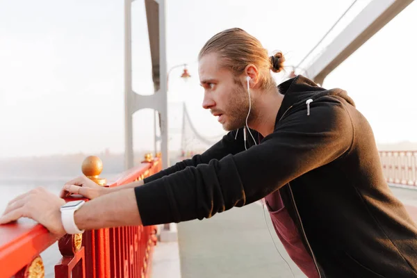 Snygg Ung Passform Idrottsman Lyssnar Musik Med Trådlösa Hörlurar Bro — Stockfoto