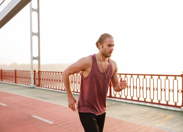 Fešák Mladý Fit Sportovec Běhání Mostě Nosí Bezdrátové Sluchátka — Stock fotografie