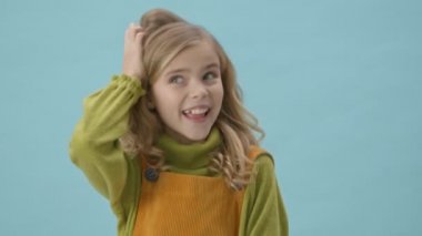 Dans eden ve mavi arka planda izole edilmiş kamerayı gösteren neşeli bir kızın portresi.