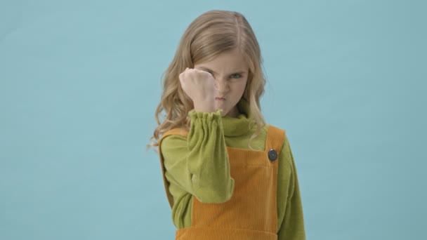Kızgın Küçük Kız Mavi Arka Planda Izole Edilmiş Kameraya Yumruğunu — Stok video