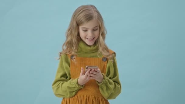 Jong Lachend Meisje Glimlachen Met Behulp Van Smartphone Geïsoleerd Blauwe — Stockvideo