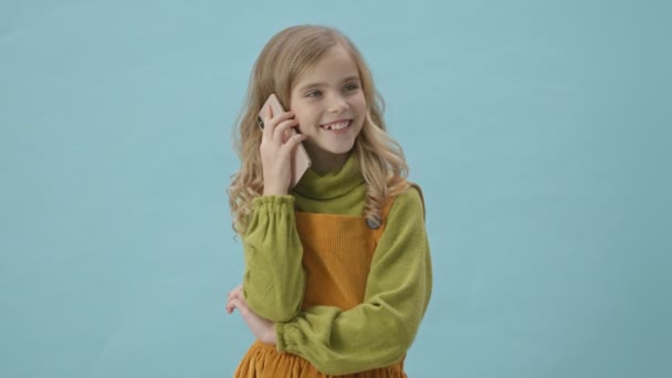 Schattig Jong Meisje Glimlachen Praten Smartphone Geïsoleerd Blauwe Achtergrond — Stockvideo