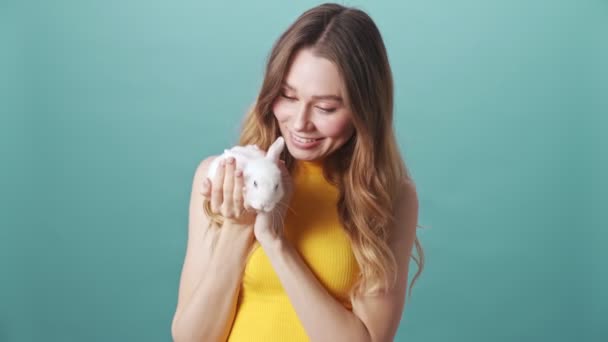 아리따운 소녀가 배경에 고립된 토끼를 붙들고 쓰다듬는다 — 비디오