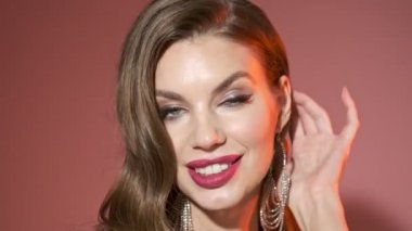 Parlak pullu güzel bir kadının kırmızı arka planda poz verip etrafa baktığı yakın plan görüntüsü.