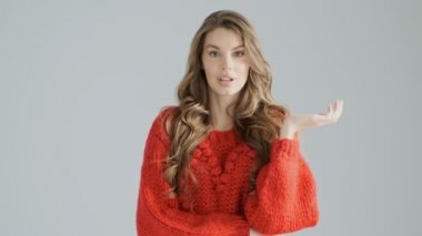 Güzel bir sürpriz genç bir kadın elini kaldırıyor Stüdyoda gri bir arka plan üzerinde izole