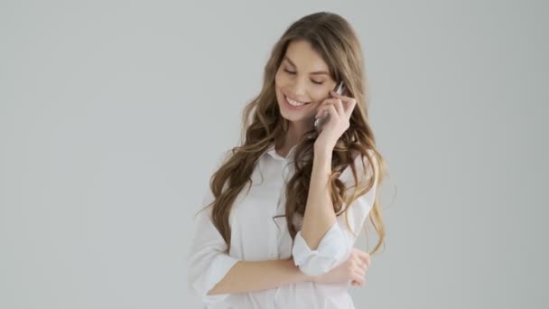 Een Glimlachende Jonge Vrouw Praat Aan Telefoon Geïsoleerd Een Grijze — Stockvideo