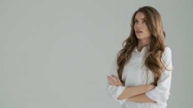 Hoşnutsuz bir kadın, sıkıcı bir suratla stüdyodaki gri bir arka plandan izole edilmiş anlamsız içeriği gösteren bir tarafa bakıyor.
