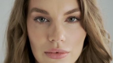 Baştan çıkarıcı flörtöz bir kadının yakın plan görüntüsü stüdyodaki gri bir arka plandan izole edilmiş dudaklarını ısırıyor.