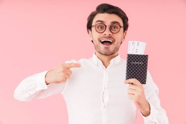 Gözlüklü, elinde gözlüklü ve pembe arka planda izole edilmiş biletleri olan beyaz bir adamın resmi.