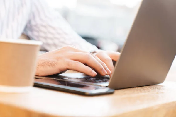 Foto Recortada Homem Caucasiano Digitando Laptop Usando Celular Enquanto Bebe — Fotografia de Stock