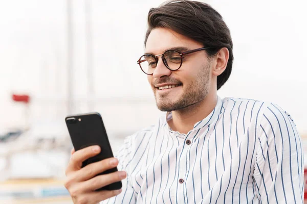Photo Handsome Young Man Wearing Eyeglasses Typing Cellphone Smiling While — Stock Photo, Image