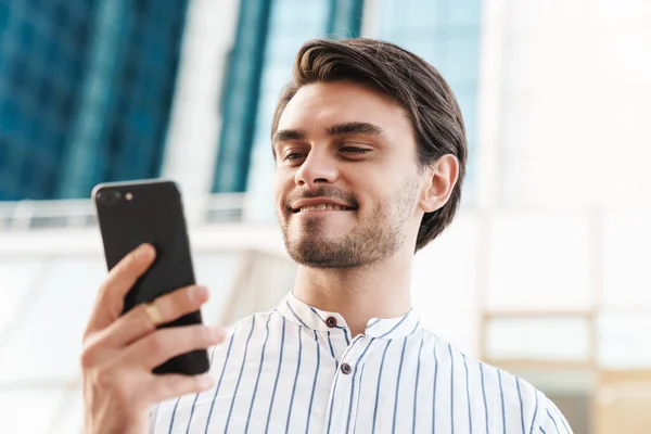 Photo Happy Young Man Wearing Striped Shirt Typing Cellphone Smiling — Stock Photo, Image