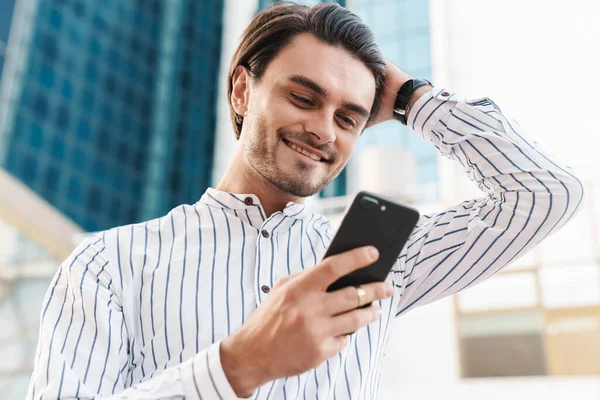 Photo Happy Handsome Man Wearing Striped Shirt Typing Cellphone Smiling — Stock Photo, Image