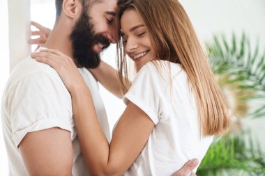 Romantik mutlu çiftin evde dans ederken kucaklaşması ve gülümsemesi.