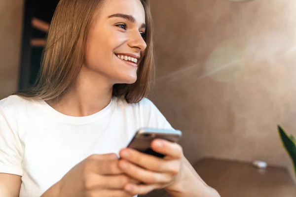 Фотографія Радісної Молодої Жінки Яка Використовує Мобільний Телефон Посміхається Сидячи — стокове фото