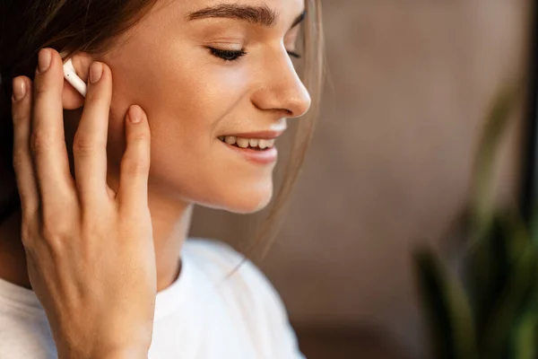 Foto Van Tevreden Jonge Vrouw Glimlachend Met Behulp Van Oortjes — Stockfoto