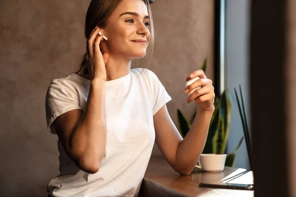 Foto Joven Mujer Feliz Bebiendo Café Uso Auriculares Mientras Está — Foto de Stock