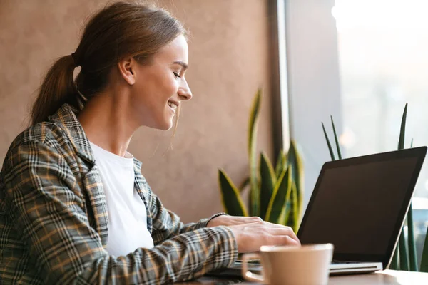 Foto Mujer Encantadora Sonriente Bebiendo Café Escribiendo Ordenador Portátil Mientras — Foto de Stock