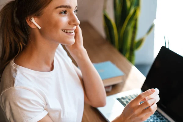 Foto Donna Carina Sorridente Utilizzando Laptop Auricolari Mentre Seduto Accogliente — Foto Stock