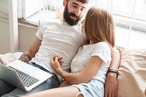 Obraz Romantyczny Zadowolony Para Pomocą Laptopa Przytulanie Leżąc Łóżku Jasnym — Zdjęcie stockowe