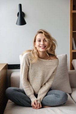 Evde poz veren güzel, iyimser genç bir kadının görüntüsü..