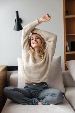 Evde poz veren mutlu, iyimser genç bir kadının görüntüsü..