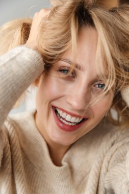 Evde oturup gülerek poz veren mutlu, iyimser genç bir kadının görüntüsü..