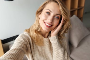 Evde gülümseyen güzel bir genç kadın resmi. Selfie çekin..