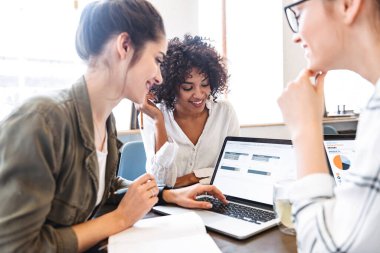 Kafede birlikte ders çalışan çoklu etnik kökenli, neşeli genç bayanların olduğu bir grubu kapatın.
