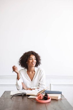 Çekici genç bir kız öğrenci kafenin içinde ödev yapıyor, kitap okuyor.