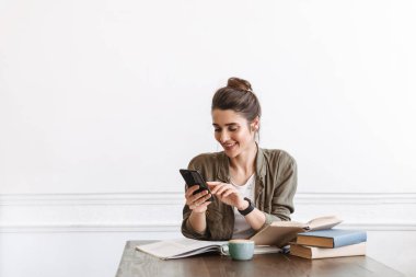 Çekici genç bir kız öğrenci kafenin içinde ödev yapıyor, kitap okuyor.