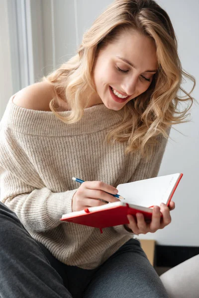 Zdjęcie Szczęśliwej Optymistycznej Młodej Kobiety Domu Piszącej Notatki Notatniku Przy — Zdjęcie stockowe