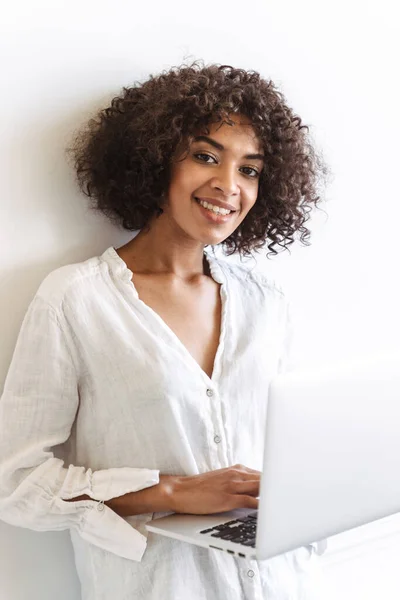 Sonriente Joven Africana Pie Pared Blanca Interior Utilizando Ordenador Portátil — Foto de Stock