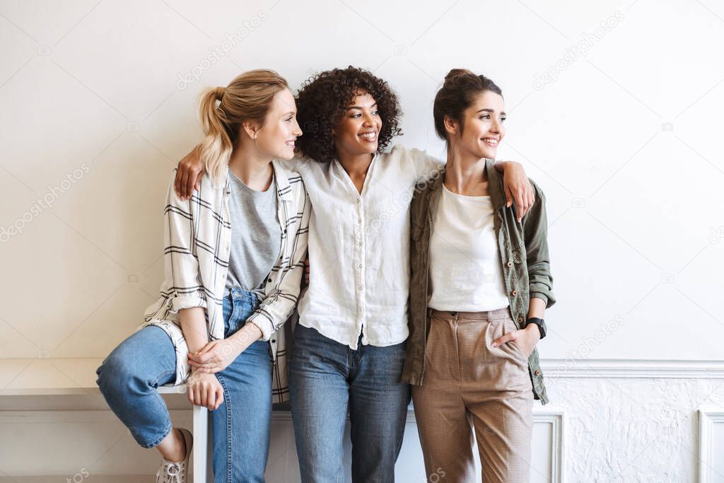 Cheerful girls standing at white wall indoors