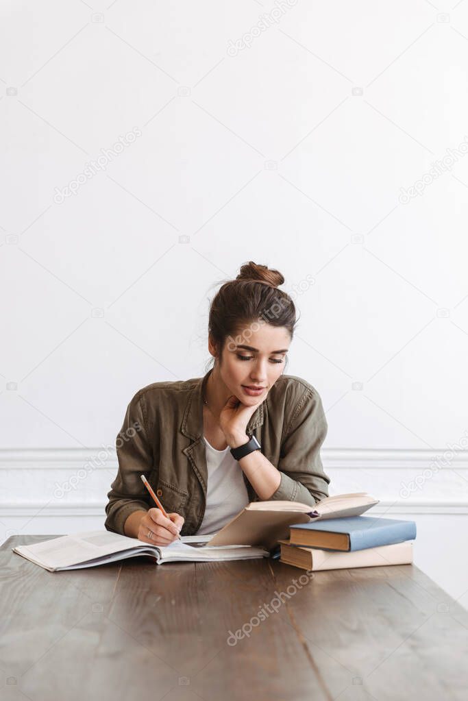 Attractive young girl student doing homework at the cafe indoors, reading books