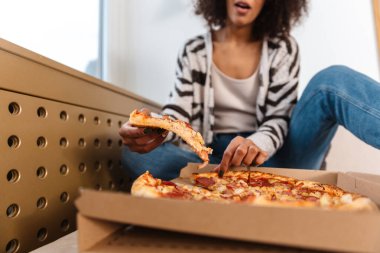 Evde güzel bir Afrikalı kadının kesilmiş fotoğrafı. Pizza yiyor..