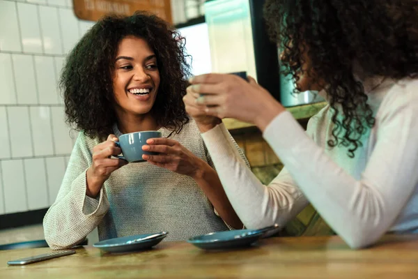 Zwei Fröhliche Junge Afrikanische Freundinnen Sitzen Café Und Trinken Kaffee — Stockfoto