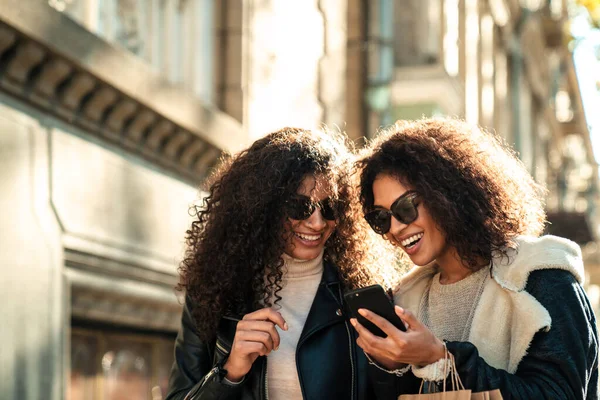 两个年轻貌美的非洲姑娘一起走在街上 用手机聊天 — 图库照片