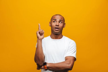 Çekici, kendine güveni tam genç bir Afrikalı adamın portresi sarı arka planda duruyor ve fotokopi alanını işaret ediyor.