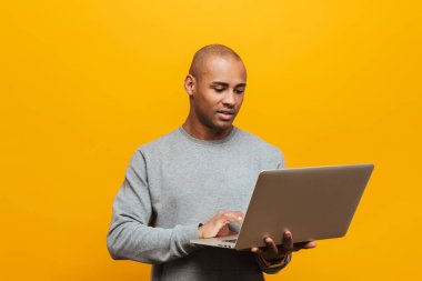 Çekici, kendinden emin genç bir Afrikalı adamın portresi sarı arka planda duruyor.