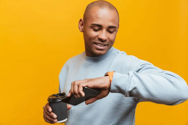 노란색 핸드폰을 사용하고 시간을 확인하는 아프리카 청년의 매력적 — 스톡 사진