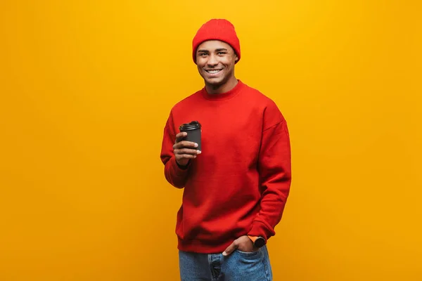 一个迷人的微笑自信的年轻非洲男子站在黄色背景上 拿着外卖咖啡杯的画像 — 图库照片