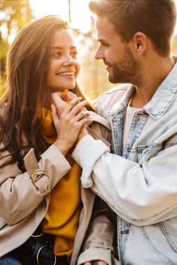 Çekici beyaz bir çiftin gülen ve sonbahar parkında birlikte yürüdüğü görüntüsü.